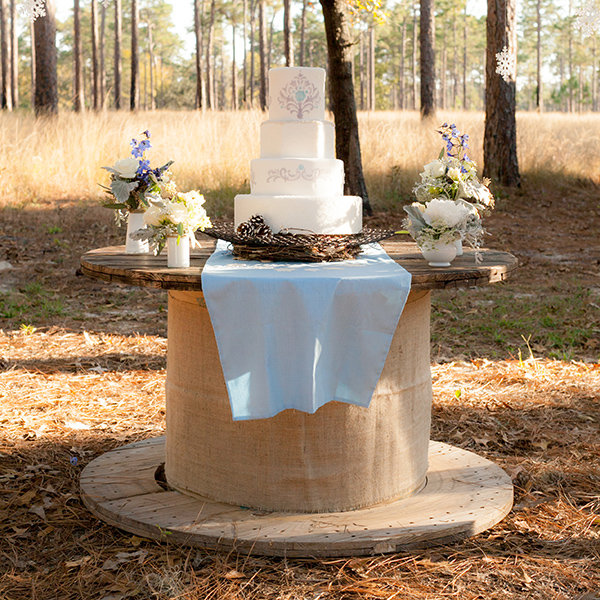 كعكة زفاف مقدمة على طاولة مبتكرة على شكل صندوق خشبي وتعد طريقة تقديم مثالية لحفلات الزفاف الريفية
