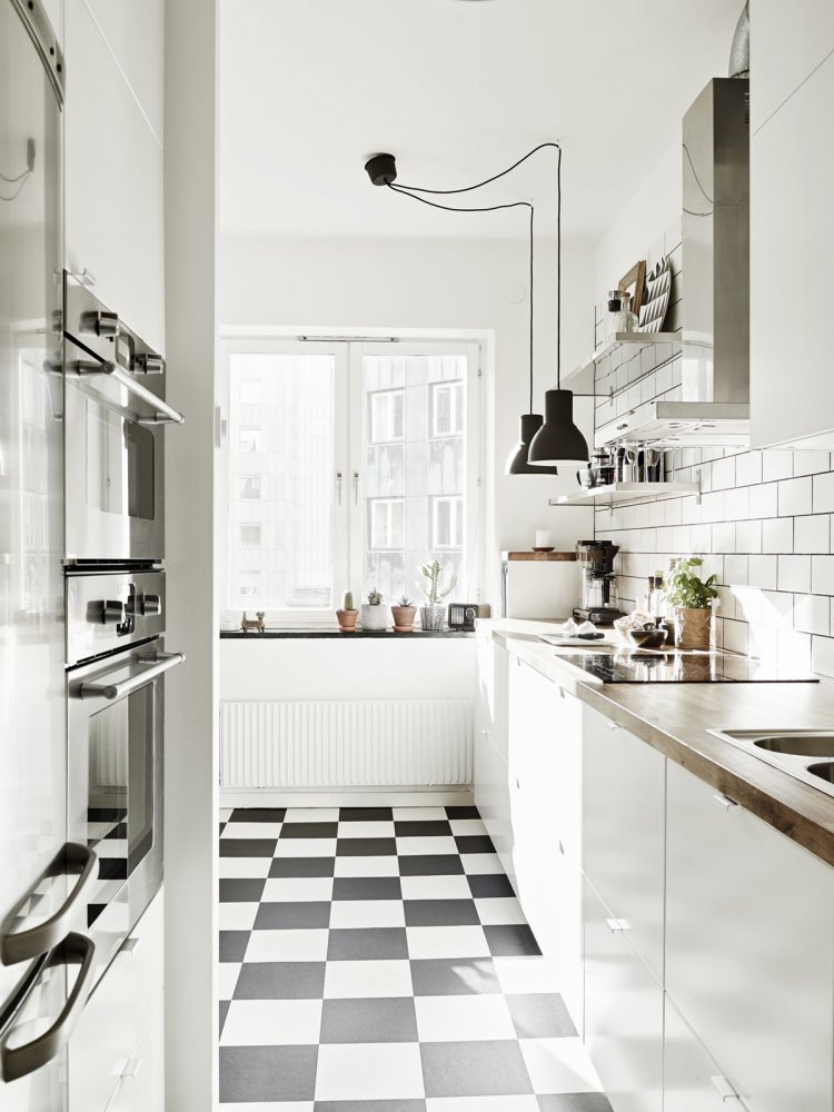 مطبخ باللون الأبيض الصريح مع أرضية مربعات تضفي عليه هوية وتميز