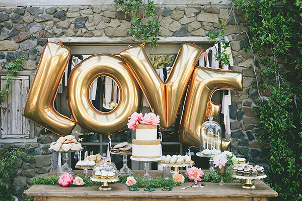 كعكة زفاف مقدمة على طاولة طعام طويلة وفي خلفيتها مجموعة من بالونات الزينة
