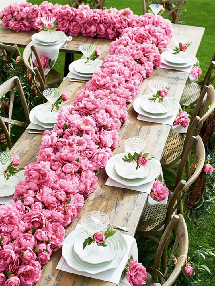 طاولات الزفاف مزينة بالورود من اللون الزهري لحفل الزفاف في حديقة المنزل